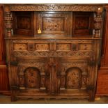 A 17th century style heavily carved oak court cupboard with marquetry inlay and bulbous supports,