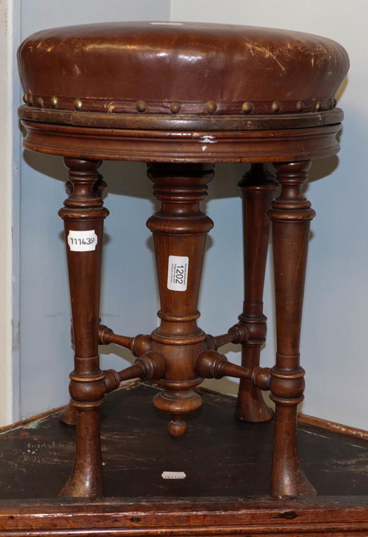 A Victorian mahogany rise and fall piano stool, raised on turned supports and with X frame cross