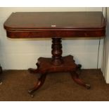 A Regency mahogany fold-over tea-table, raised on a turned centre pedestal on carved scroll