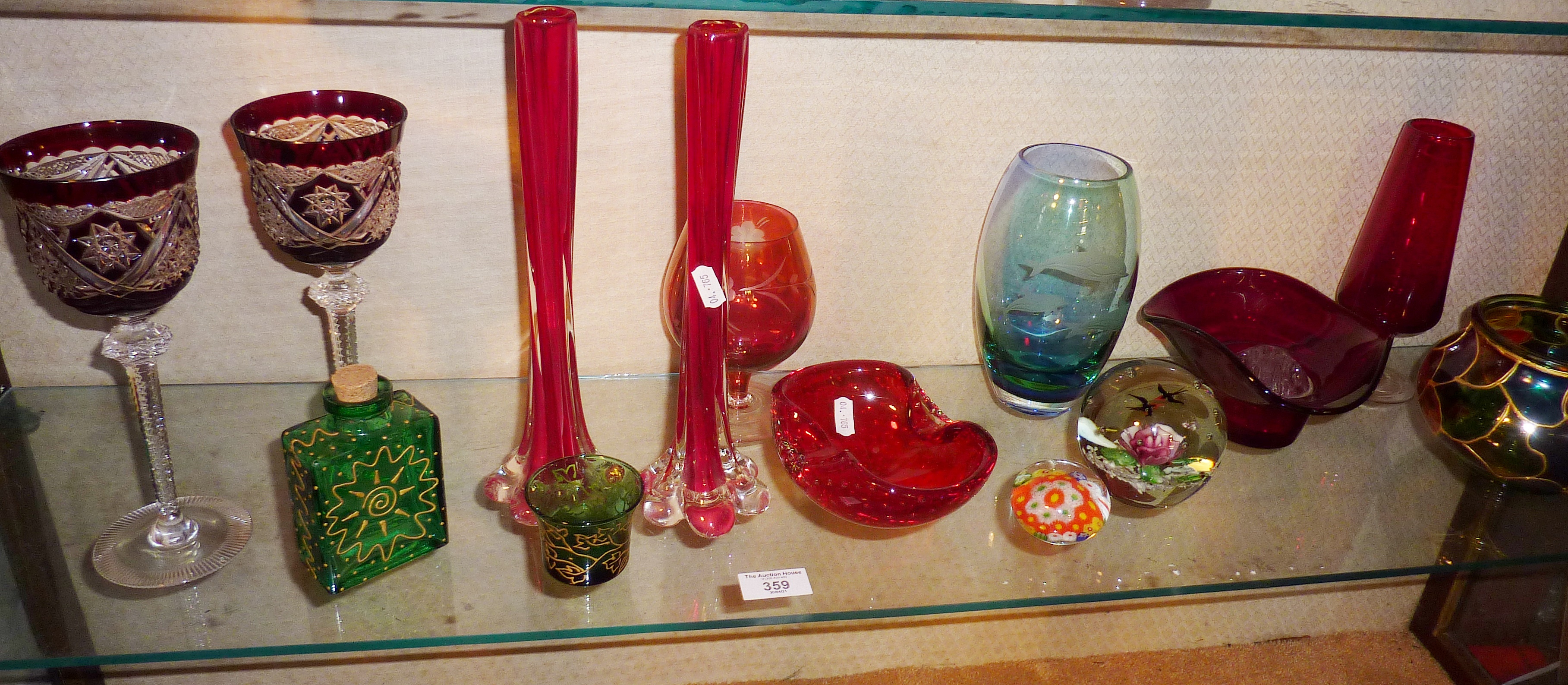 Shelf of assorted coloured glass, inc. paperweights