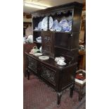 Late Victorian carved oak dresser, the upper section having shelves and central cupboard over two