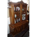 Continental walnut display cabinet of two arched doors above serpentine fronted lower section with