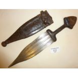 Tribal Art: An African dagger in a leather sheath, engraved decoration to the blade and pommel