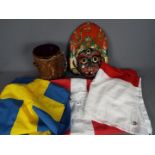 Three flags comprising Denmark, England and Sweden and an animal skin drum and painted tribal mask.