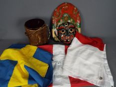 Three flags comprising Denmark, England and Sweden and an animal skin drum and painted tribal mask.