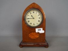 A mahogany cased lancet top mantel clock, Roman numerals to a white dial.