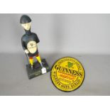 Breweriana - an oval, cast iron wall plaque and a money bank marked 'Guinness',