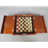 An Edwardian travelling chess set with diptych board and miniature bone pieces in natural and red