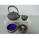 A cloisonné lidded trinket box of circular form, decorated with flowers against a black ground,