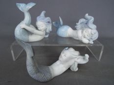 Lladro - A set of three Lladro matte white porcelain figurines depicting mermaids comprising