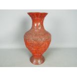 A cinnabar lacquer vase decorated with scholars and attendants in a mountainous landscape,