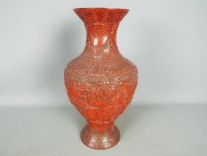 A cinnabar lacquer vase decorated with scholars and attendants in a mountainous landscape,