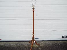 A wooden standard lamp on tripod supports with gilt detailing,