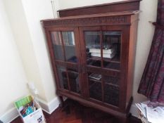 A freestanding glazed bookcase having twin doors with carved decoration,