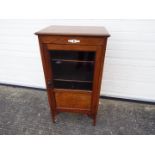 An Edwardian mahogany cabinet, the glazed door opening to reveal a four-tier shelved interior,