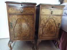 A pair of walnut veneered bedside cabinets each raised on four supports, with protective glass tops,