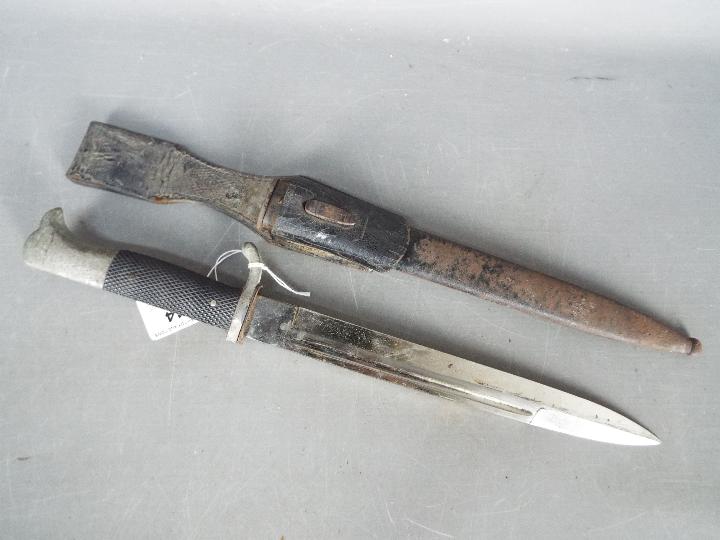 A German dress bayonet with 9 3/4" blade with WKC makers mark, black composite grip, with scabbard.