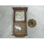 An oak cased wall clock with key and pendulum and brass sundial.