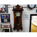 A highly carved walnut double weight Vienna wall clock with ceramic dial and pendulum