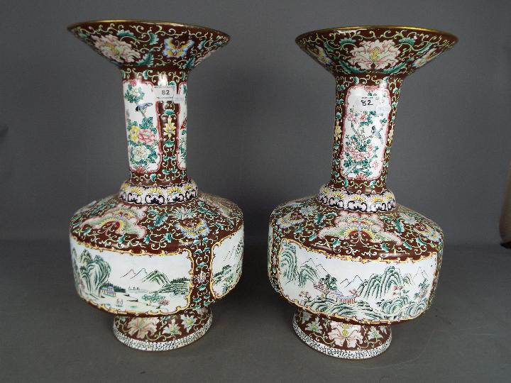 A large pair of Chinese enamel vases decorated to the body with panels of landscape scenes,