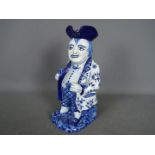 A Delft style blue and white toby jug modelled as a standing man with glass and pipe,