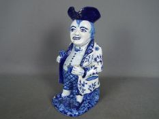 A Delft style blue and white toby jug modelled as a standing man with glass and pipe,