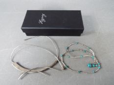 Two silver necklaces contained in a black box