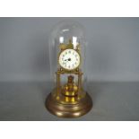 A brass torsion clock with disc pendulum, under glass dome, approximately 31 cm (h).