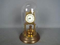 A brass torsion clock with disc pendulum, under glass dome, approximately 31 cm (h).