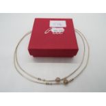 A silver necklace contained in a red box,