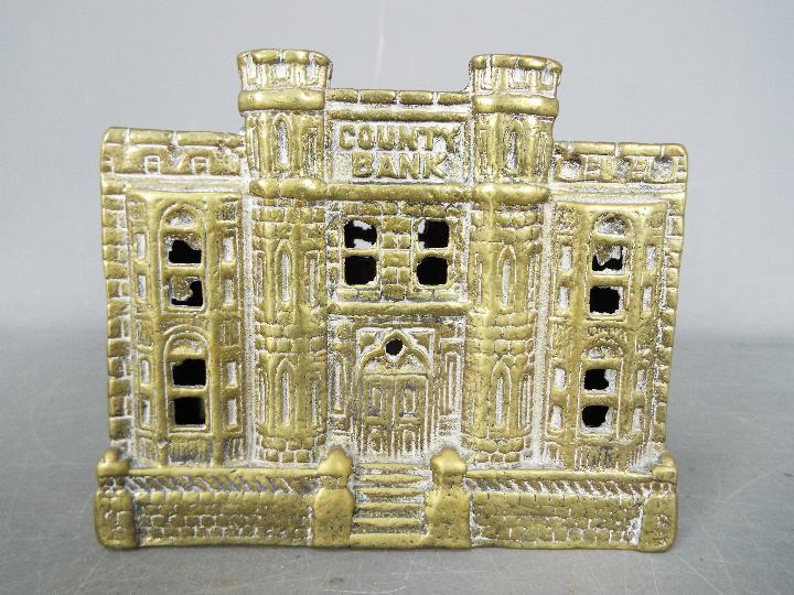 A cast brass 'County Bank' money bank, approximately 10.5 cm (h).