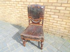 A low side chair with carved detailing and leather upholstered seat and backrest.