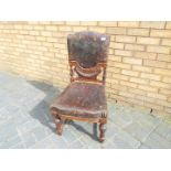 A low side chair with carved detailing and leather upholstered seat and backrest.