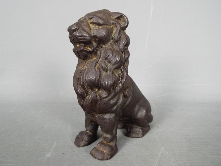 A cast iron money bank in the form of a seated male lion,