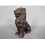 A cast iron money bank in the form of a seated male lion,