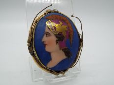 A vintage, painted brooch of oval from depicting a lady in profile with yellow metal mount,