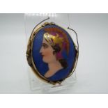 A vintage, painted brooch of oval from depicting a lady in profile with yellow metal mount,