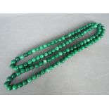 A large single strand necklace of polished malachite beads, each bead approximately 1.