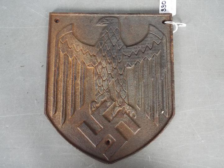 A cast iron German type plaque with depiction of eagle and swastika, approximately 24 cm x 20 cm.