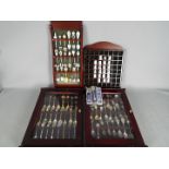 A collection of collector spoons and souvenir thimbles contained within four display cases.