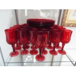 A collection of ruby glassware, wine glasses and plates.