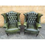 A pair of green leather wingback chairs.