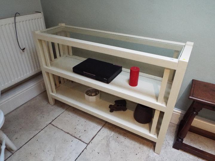 A glass topped console table, approximately 80 cm x 120 cm x 35 cm.