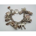 A charm bracelet with a quantity of charms variously stamped 'Silver', 'Sterling', '925'.