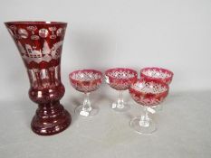 A ruby etched to clear glass vase, approximately 26 cm (h) and four cranberry cut to clear glasses.