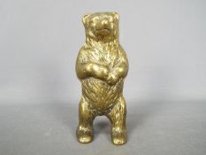 A cast brass money bank in the form of a standing bear, approximately 15.5 cm (h).