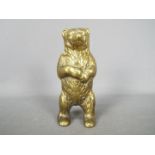 A cast brass money bank in the form of a standing bear, approximately 15.5 cm (h).