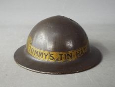 A World War One period novelty, tin money bank in the form of a helmet, titled 'Tommy's Tin Hat' 4.