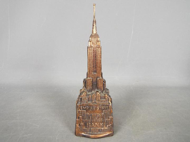 A vintage cast metal money bank of architectural form depicting the Empire State Building,
