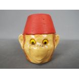 A vintage Manor Ware money bank in the form of a monkey wearing a fez, approximately 8 cm (h).